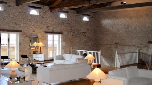 Il comprend un salon doté d'un mobilier blanc et d'un mur en briques. dans l'établissement Domaine de Perches, à Gaillac