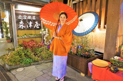a woman is holding an umbrella in a garden at Morizuya in Toyooka