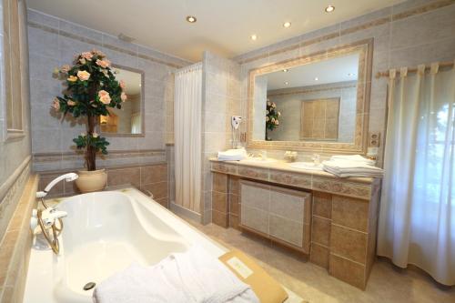 y baño con bañera, 2 lavabos y espejo. en L'Enclos des Lauriers Roses en Cabrières