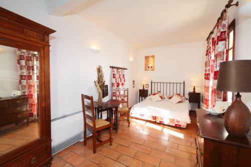 a bedroom with a bed and a desk and a table at L'Enclos des Lauriers Roses in Cabrières