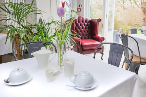 a white table with a vase of flowers on it at LLwyn Country House in Llanelli