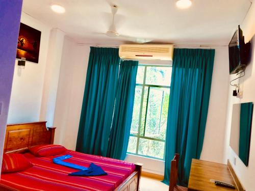 a bedroom with a bed with red sheets and a window at Travellers Halt in Ratnapura