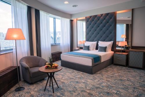 Pokój hotelowy z łóżkiem i krzesłem w obiekcie Radon Plaza w Sarajewie