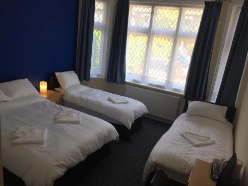 a hotel room with two beds and two windows at Southend Central Hotel - Close to Beach, City Centre, Train Station & Southend Airport in Southend-on-Sea