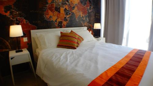 a white bed with a colorful striped pillow on it at R1103ERI by euroresort in Marsalforn