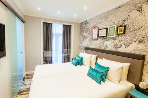 a bedroom with a large white bed with blue pillows at Oliver Plaza Hotel in London