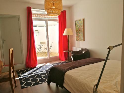 une chambre avec un lit et une fenêtre avec des rideaux rouges dans l'établissement La Loge du Theatre - Saintes, à Saintes