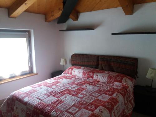 a bedroom with a bed with a red comforter and a window at Mansarda Monte Bianco in La Salle