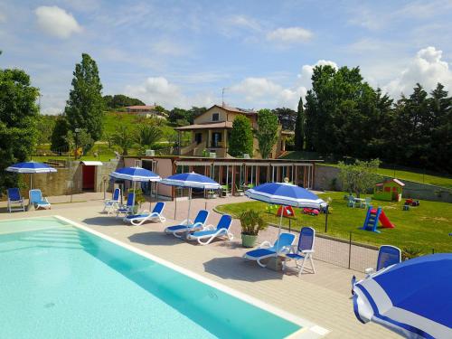 una casa y una piscina con sillas y sombrillas en Agriturismo San Gregorio en San Vincenzo
