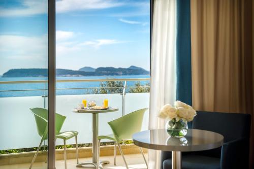 a room with a balcony with a table and chairs at Valamar Argosy Hotel in Dubrovnik