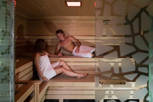 a man and woman sitting in a sauna at Hotel Zena Beauty & Shopping Center in Hévíz