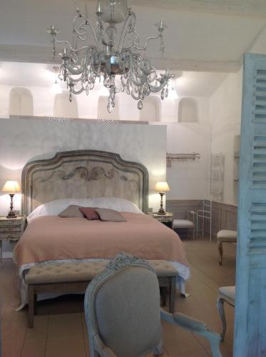 une chambre avec un grand lit et un lustre dans l'établissement Les Colombes, à Lagnes