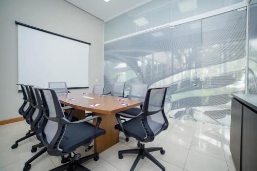 a conference room with a wooden table and black chairs at Bristol Santo André ABC São Paulo in Santo André
