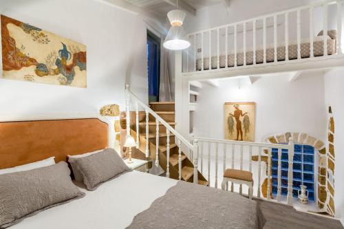 a white bedroom with a bed and a staircase at Elvie House in Chania