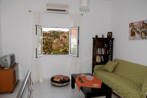 een woonkamer met een groene bank en een raam bij Faraggi Richti House in Éxo Moulianá