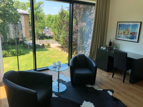a living room with chairs and a table and a large window at Voss Villa in Leipzig