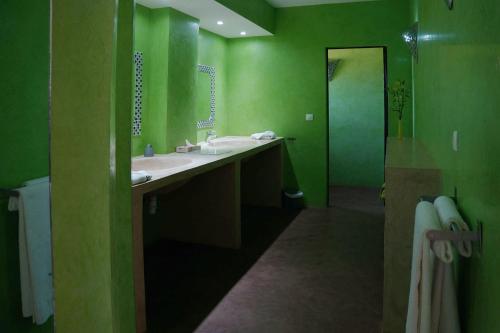 a green bathroom with two sinks and a shower at La Taniere Villa Metsu in Saly Portudal