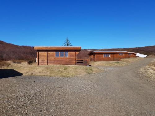 a house on a hill with a dirt road in front at Hótel Bjarkalundur in Reykhólar
