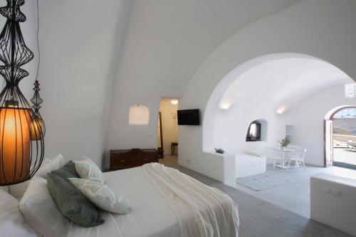 Villa Santorini 520 by Caldera Houses في أويا: غرفة نوم بيضاء مع سرير وطاولة