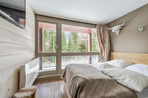 a bedroom with a bed and a large window at Résidences quartier Charmettoger - maeva Home in Arc 1800