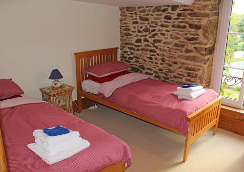 a bedroom with two beds and a stone wall at Val Rive - Leonardo Apartment in Léhon