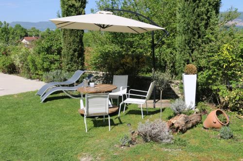 a table and chairs under an umbrella in a yard at Chambres et table L' échappée in Bouvesse-Quirieu