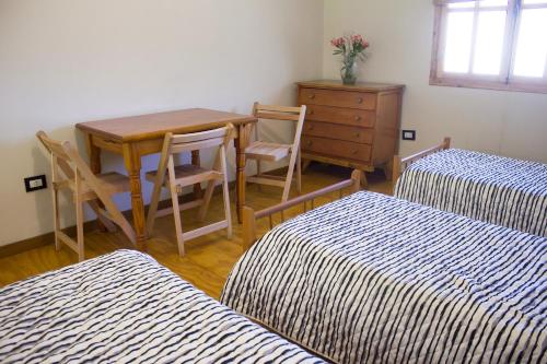 una camera con due letti, un tavolo e un comò di El Fulgor - Posada - Chacras de Coria a Mayor Drumond