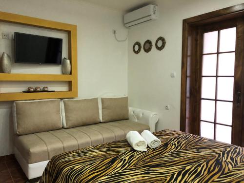 a bedroom with a bed with a couch and a flat screen tv at Queen Kodre Apartments in Ulcinj