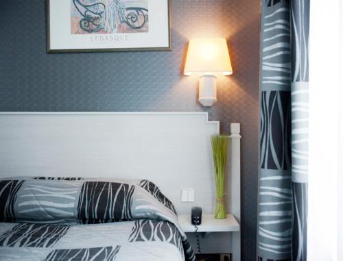 a bedroom with a bed with a white headboard and a lamp at Hotel Miramar in Paris