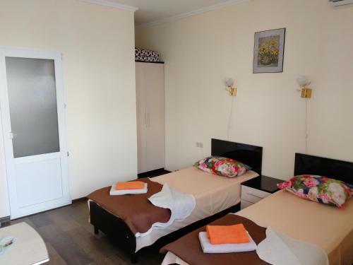 a hotel room with two beds and a table at Nadezhda Guest House in Adler