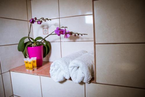 a bathroom with towels and a vase with purple flowers at Lilian View Studio in Kissamos