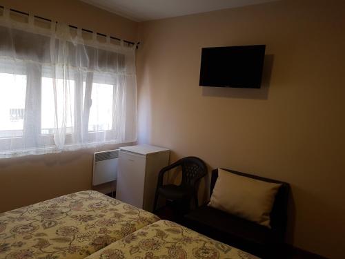 a bedroom with a bed and a chair and a television at Hostal Arenal in San Vicente de la Barquera