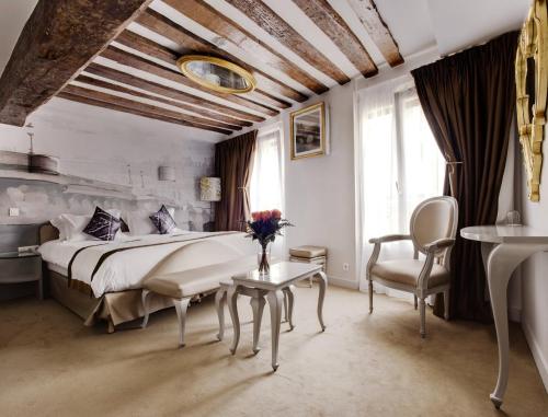 パリにあるブティック オテル コンフィダンティエルのベッドルーム1室(ベッド1台、テーブル、椅子付)