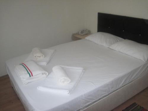 a bed with white sheets and towels on it at Bells Motel in Seferihisar