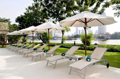 a row of lounge chairs with umbrellas at Ibis Bangkok Riverside in Bangkok