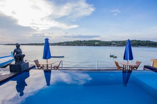 a swimming pool with two chairs and a statue and a body of water at Aurora Beach View in Nusa Lembongan