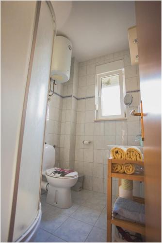 a small bathroom with a toilet and a window at Apartments Maja in Podstrana
