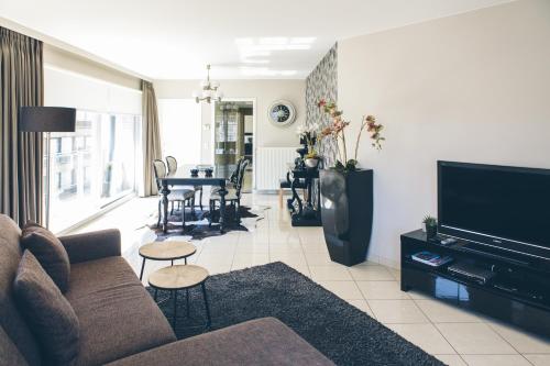 a living room with a couch and a flat screen tv at Hotel du Bassin in Ostend