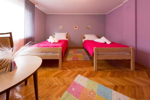 2 letti in una camera con pareti viola e pavimenti in legno di Apartman Antea a Otočac