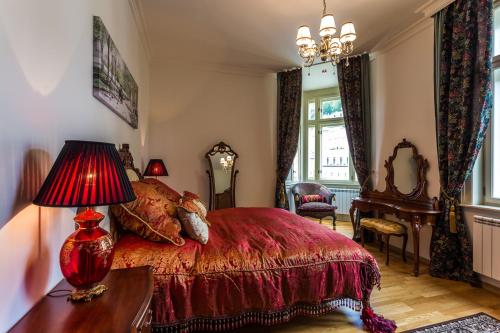 a bedroom with a red bed and a table with a lamp at Karlsbad Prestige in Karlovy Vary