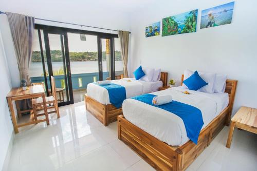 a bedroom with two beds and a balcony at Aurora Beach View in Nusa Lembongan