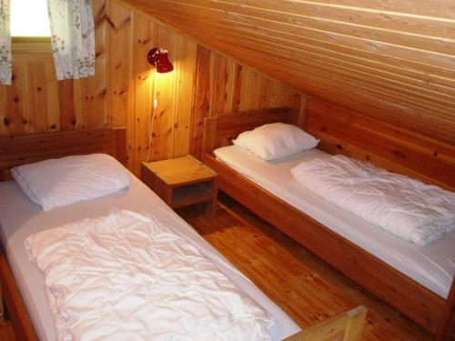 two beds in a room with wooden walls at Hogstul Hytter - Apartment South in Tuddal