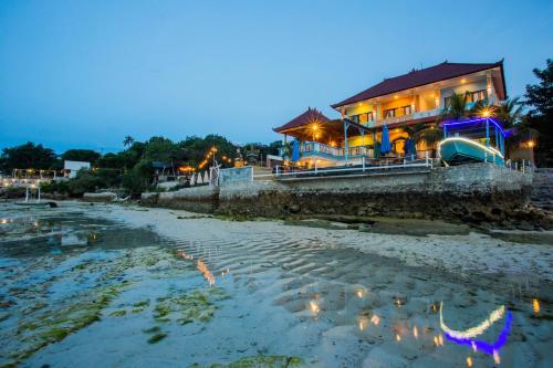 a house on the shore of a beach at night at Aurora Beach View in Nusa Lembongan