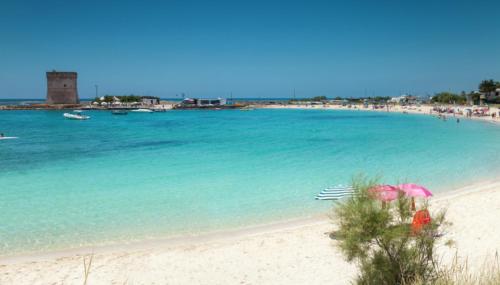a beach with umbrellas and people in the water at Bed Nonnonino in Porto Cesareo
