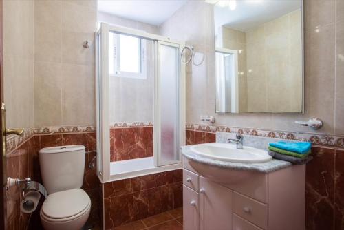 y baño con aseo, lavabo y espejo. en Lovely, new, bright 3 mins to beach apt 105 sq meters, en Alicante