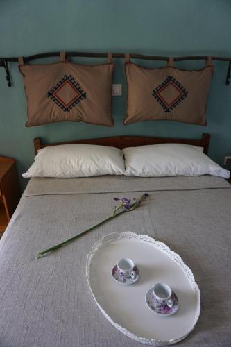 a bed with a tray with two cups and flowers on it at Country Studios in Karpathos