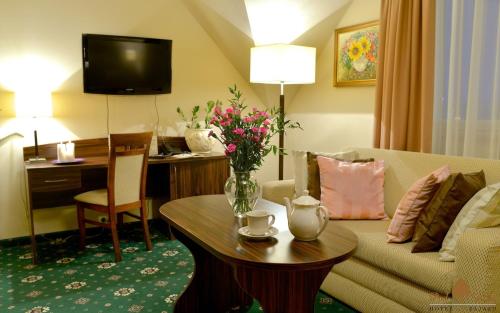 a hotel room with a couch and a table with flowers on it at Zajazd Pod Lipą in Humniska