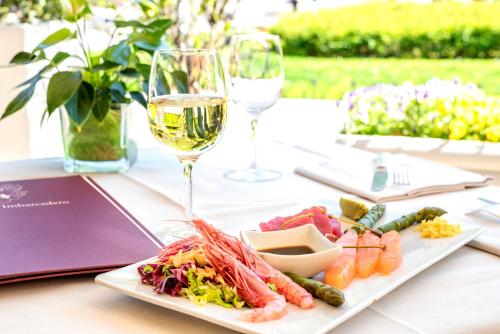 a table with a plate of food and glasses of wine at Hotel Metropole Suisse in Como