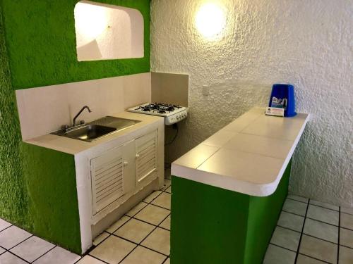 a green and white kitchen with a sink and a stove at Suites Santa Barbara in Manzanillo