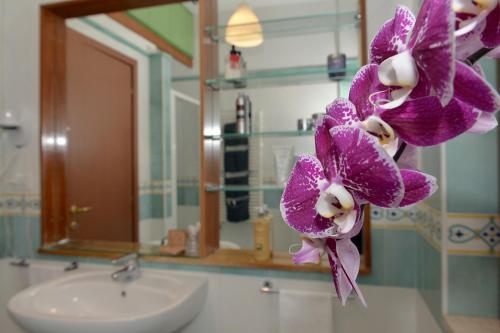 a bathroom with a sink and purple flowers on a counter at Tizi Apartments Corso Reginna in Maiori